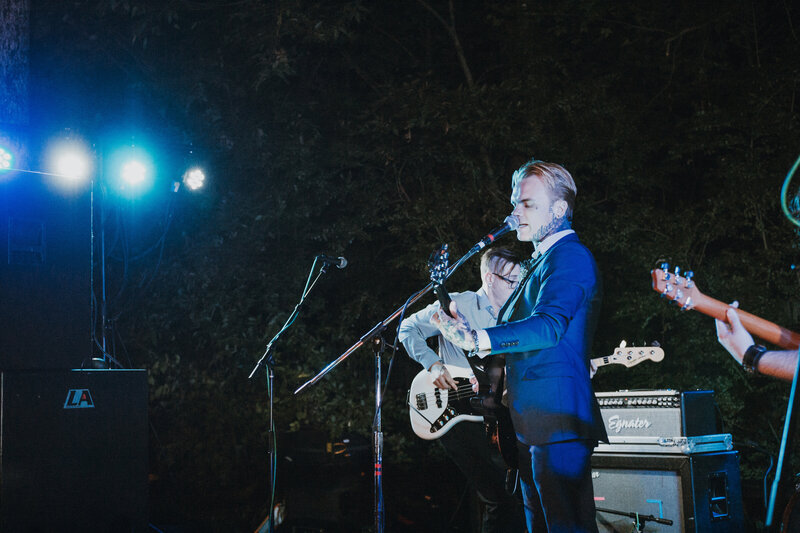 man in blue suit singing and playing guitar