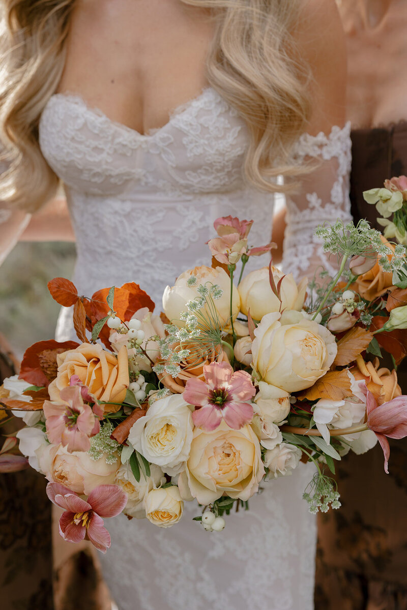 Black and white image of a bride and groom walking hand in hand through a field, as the brides vail trails behind and catches the golden hour light