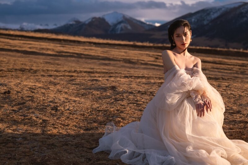Couture dress bridal shoot on a field with mountains in the background and golden light.
