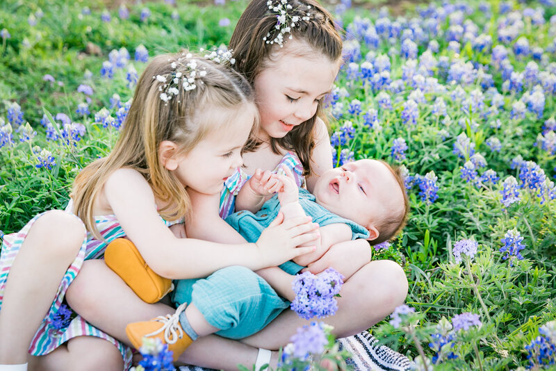 Young girls holding their baby brother in a fields of bluebonnets, Austin Family Photographer