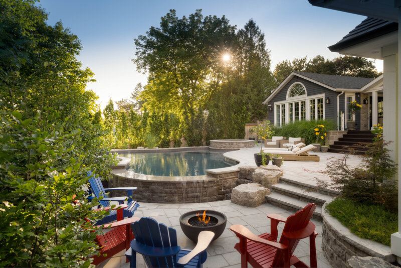 stone infinity pool with attached hottub and muskoka chair lounges and a firepit