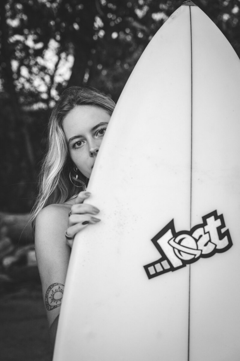 A girl peaking behind a surfboard