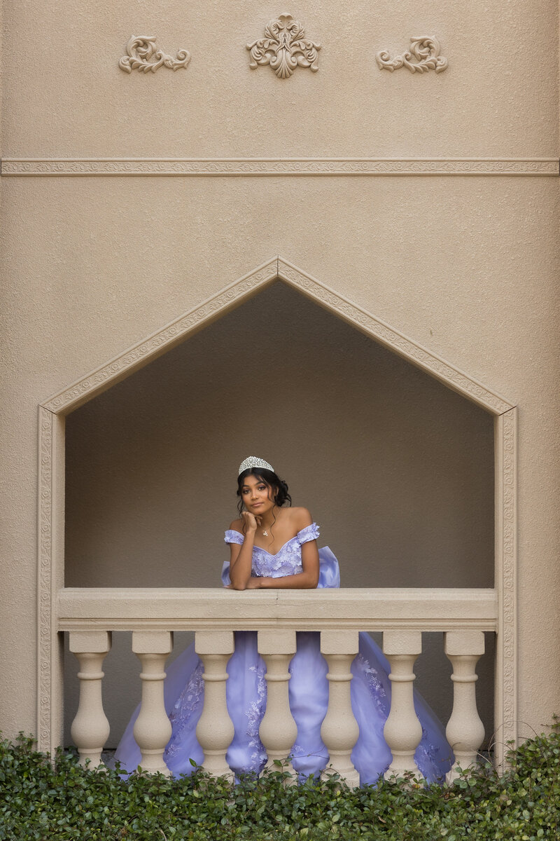 woman in quinceanera dress standing in front of large stone building