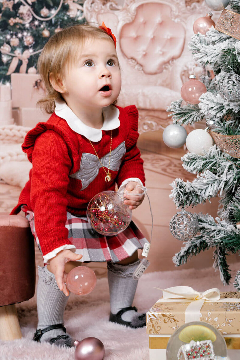 A couple embracing near a stone bridge by the water, with the groom gently holding the bride as she leans into him, captured during a romantic coastal engagement session by a UK wedding photographer.