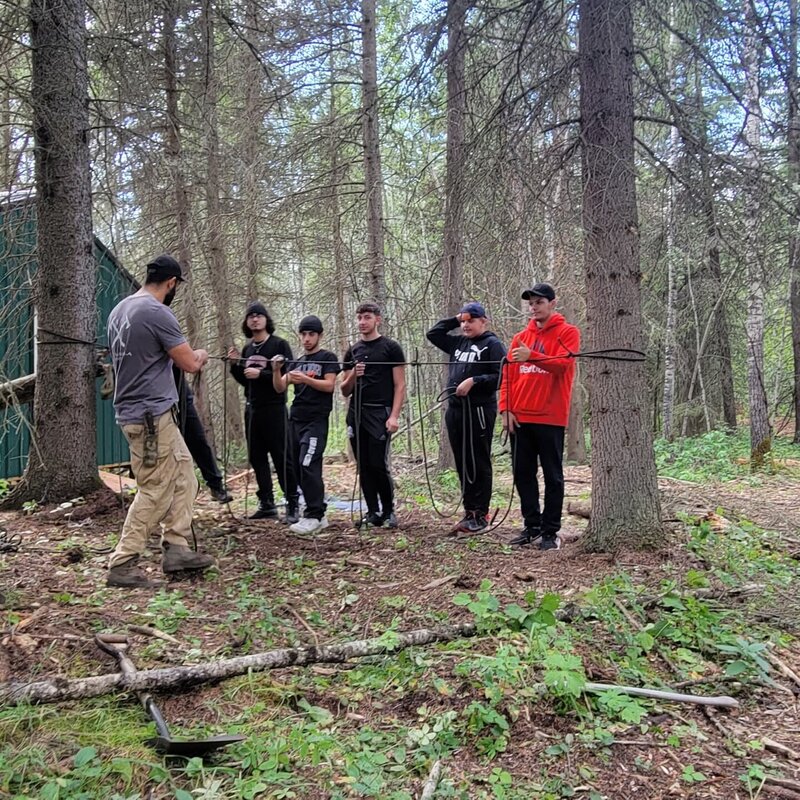 Leaders participating in experiential training in a forest setting, building trust, resilience, and communication under pressure