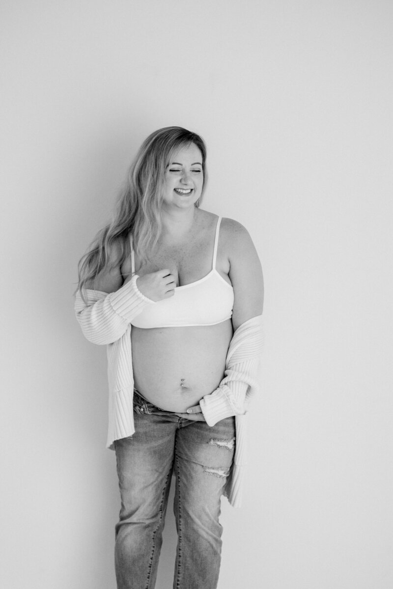 Woman with a happy face photographed in the studio snuggling her pregnant belly