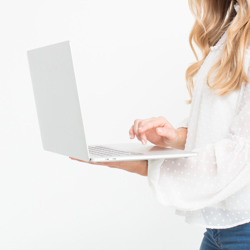 woman standing in white room with macbook working