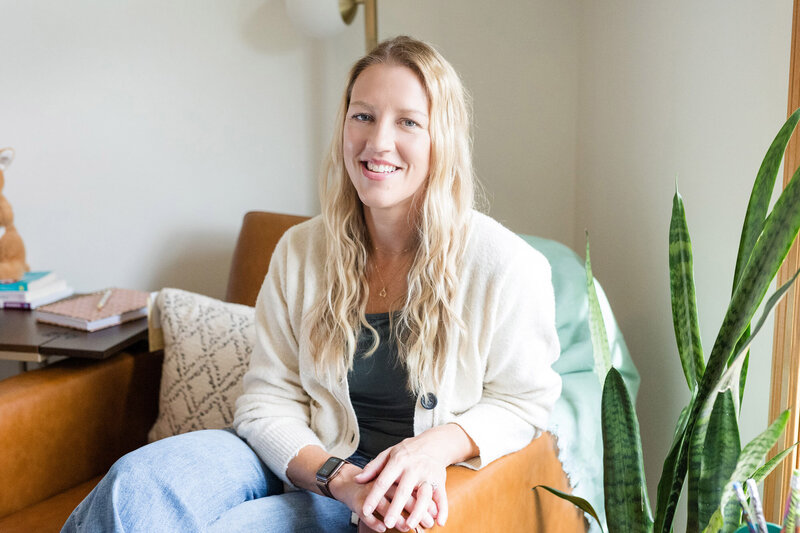 Parent coach Amy Fink sitting in her office next to a tall green plant