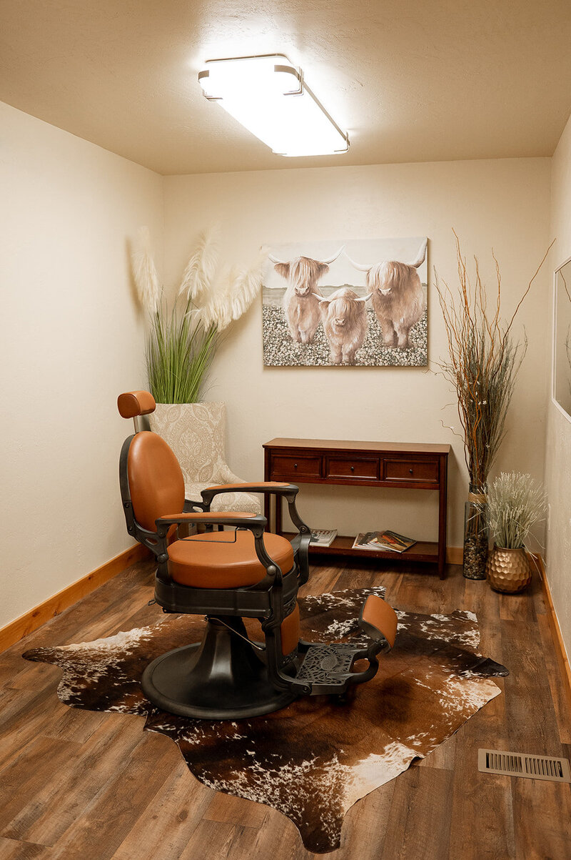 An exam room at Kalispell Denture studio, featuring a vintage style leather chain, cowhide rug, and boho vases and wall art.