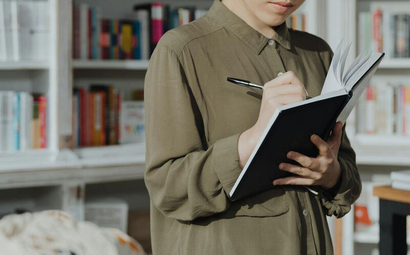Une jeune femme écrit son livre à la main sur un carnet