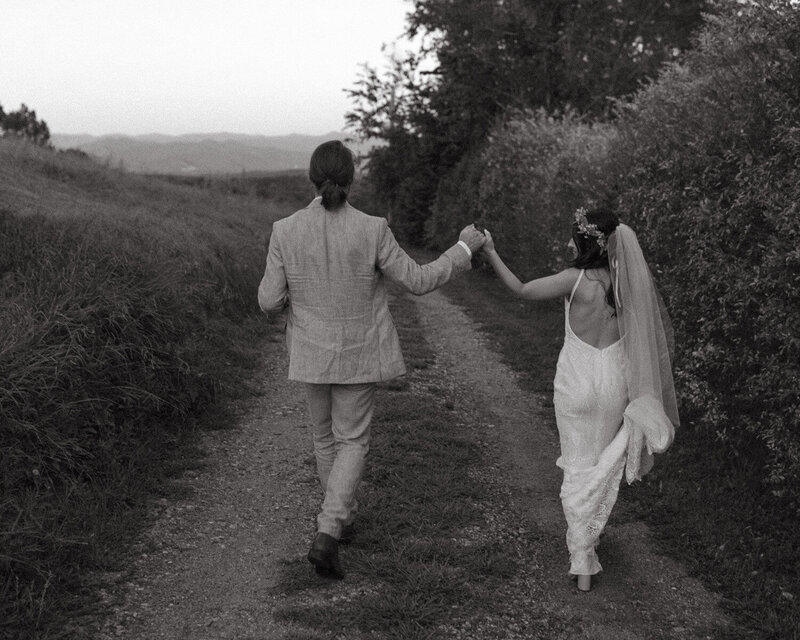 a bride and a groom walking down a path