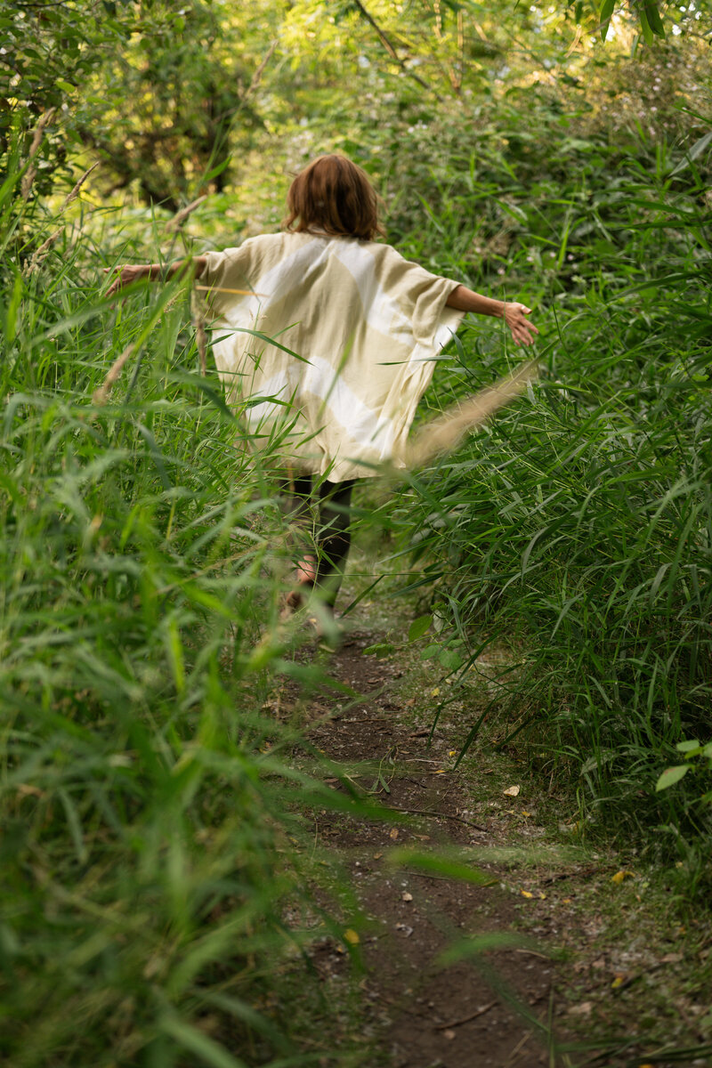 yoga teacher joyously running through a green field
