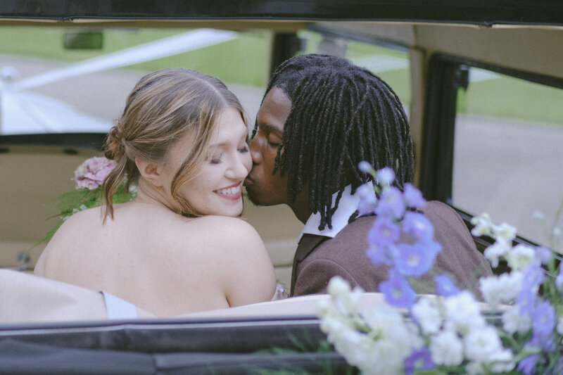 bride smiling and groom kissing her cheek in a vintage car in Iceland 