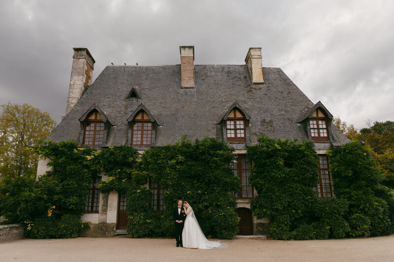 photo of bride and groom standing in front of large brick house taken by New York City Hall wedding photographer