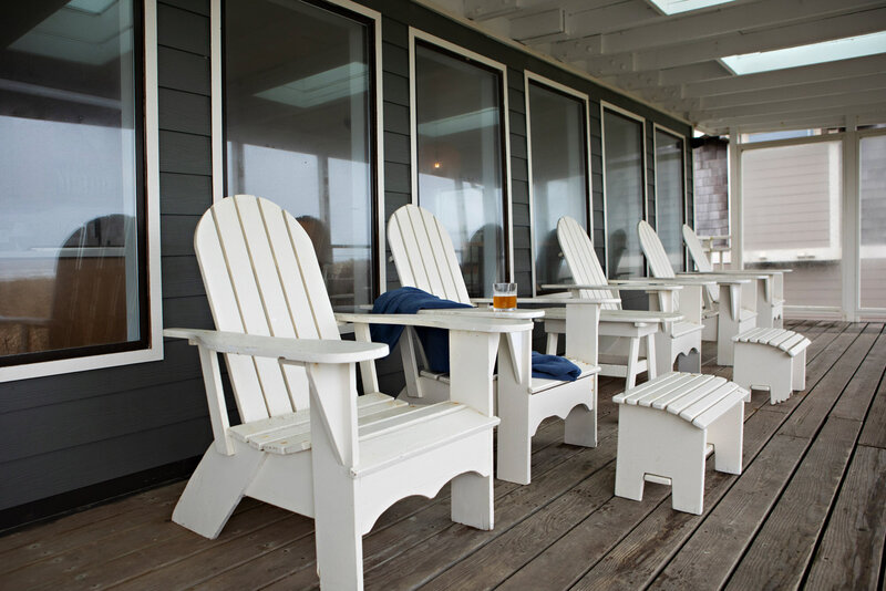 A Coastal home outdoor seating featuring white adirondack chairs, representing an example of work in Winsome Home's Interior Design Portfolio. 