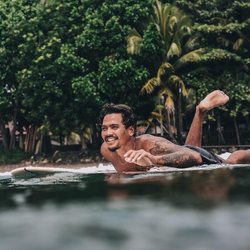 Longboard surf coach Akaa paddling out - Santai Retreats Indonesia