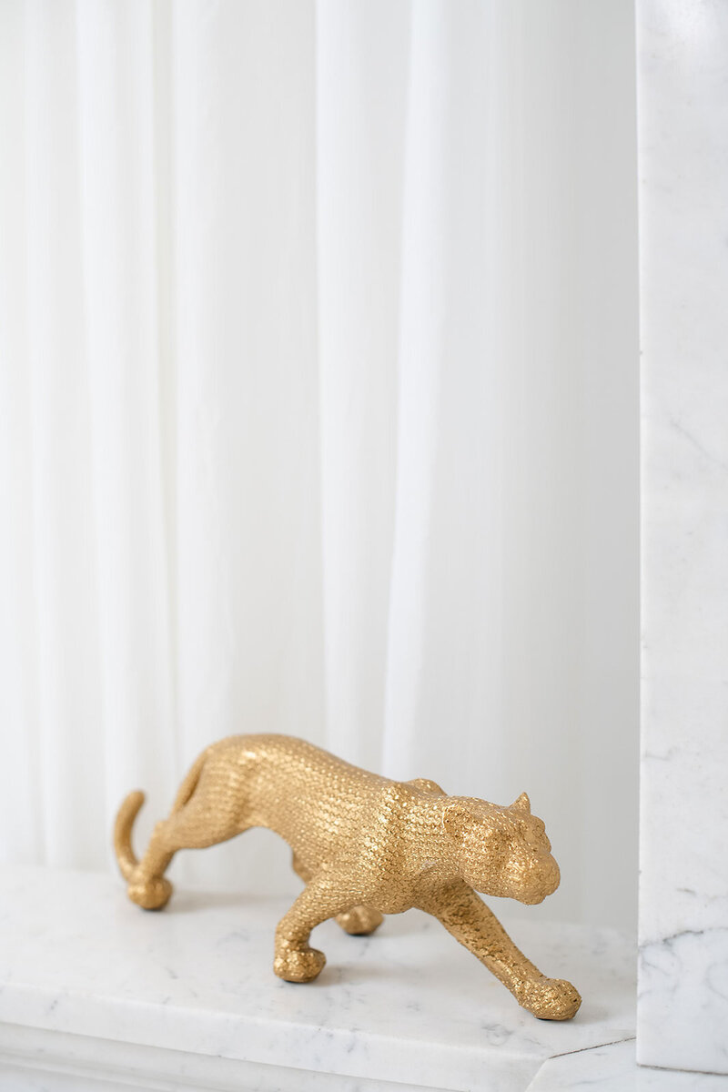 Gold statue of a panther sitting on marble railing
