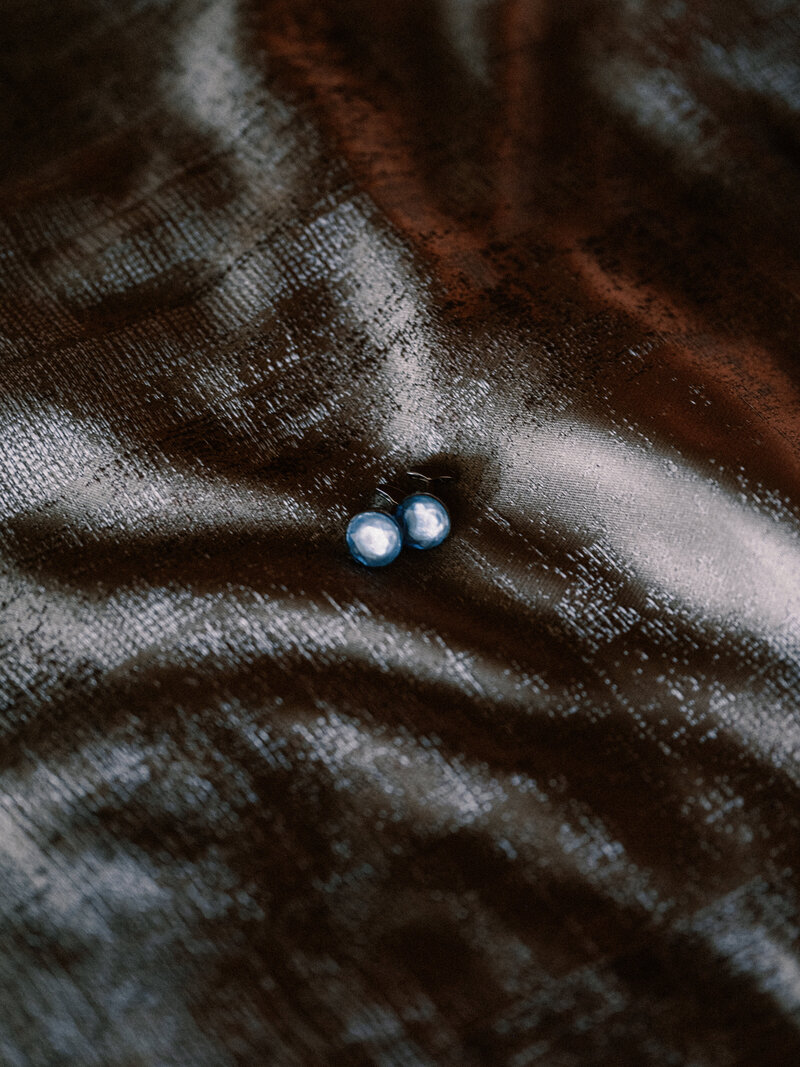 Macro photograph shows dark textured surface with tiny buttons creating a reflective pattern in low light.