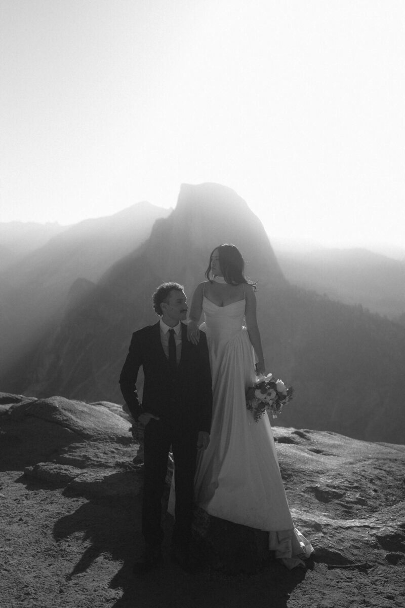 Yosemite elopement: Couple stands dramatically looking into the distance in black and white