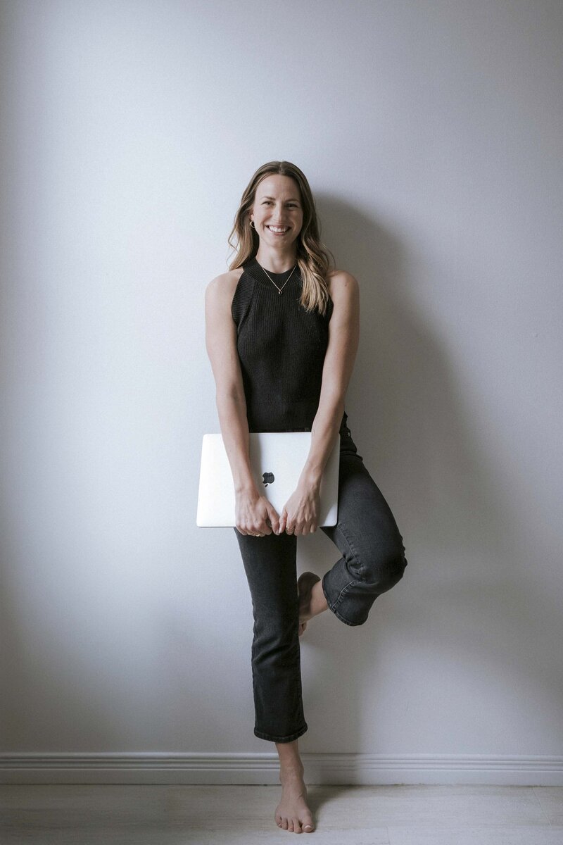 Yoga and Pilates instructor holding a laptop, ready to guide clients through personalized online sessions.