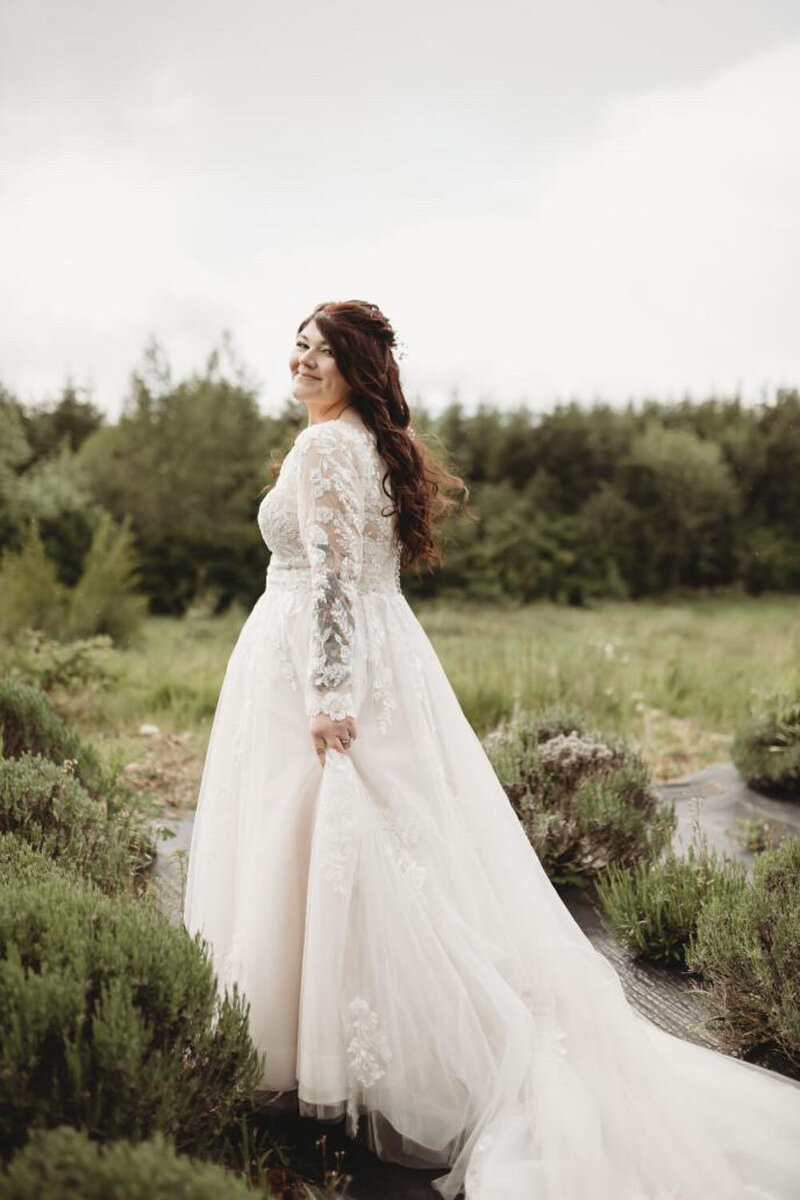 A bride in a long-sleeve gown standing in a lavender field