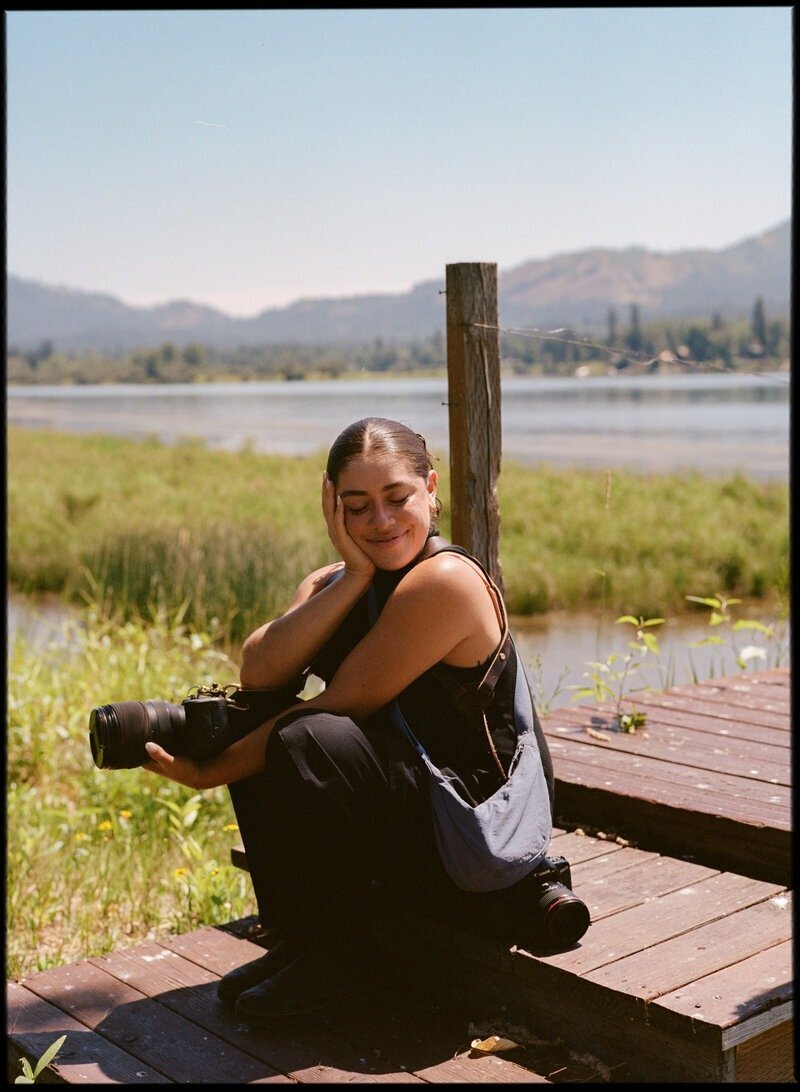 Puerto Rico photographer sitting on lakeside dock holding camera during golden hour

