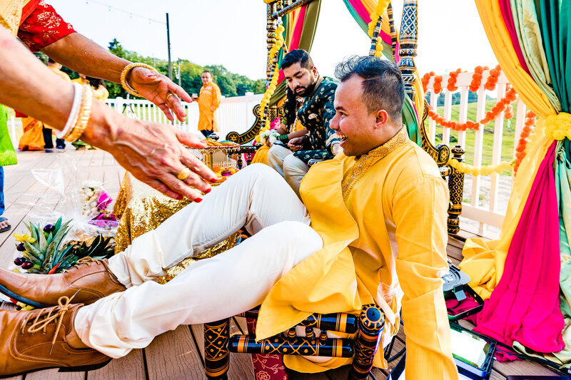 A wedding guest falling through a chair during the ceremony while he laughs and someone is trying to grab him