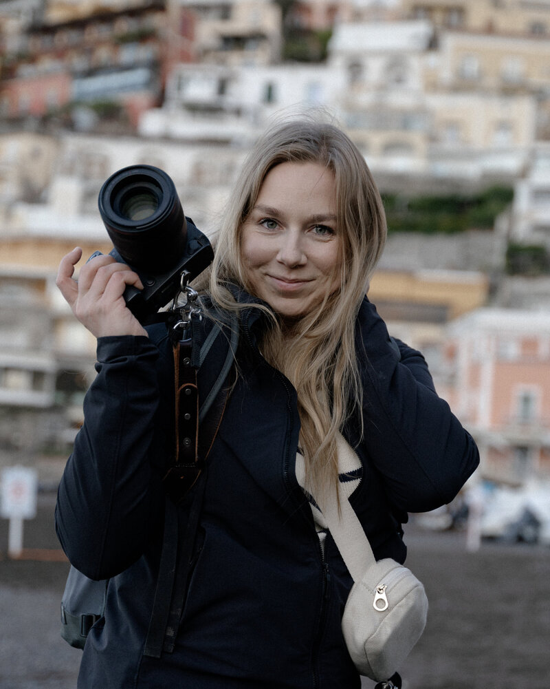 A photographer holding a camera and smiling.
