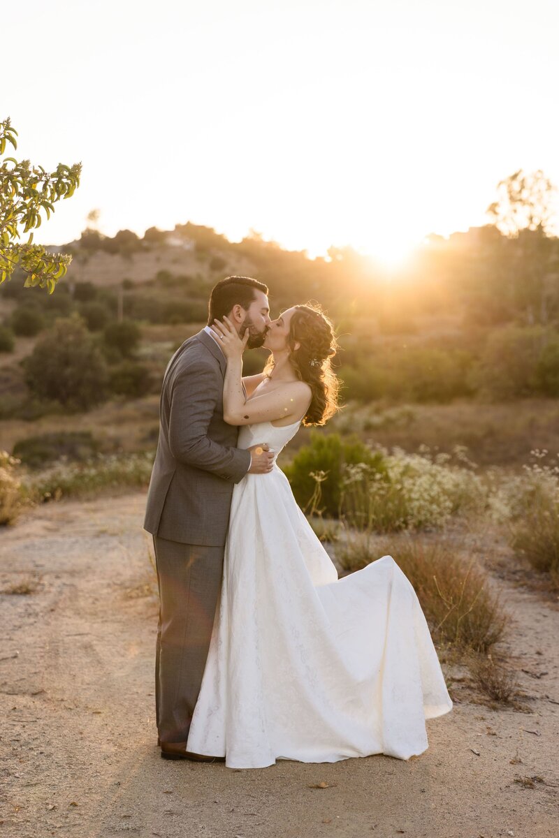 Newly married bride and groom, outside at Point Vicente, embracing during sunset