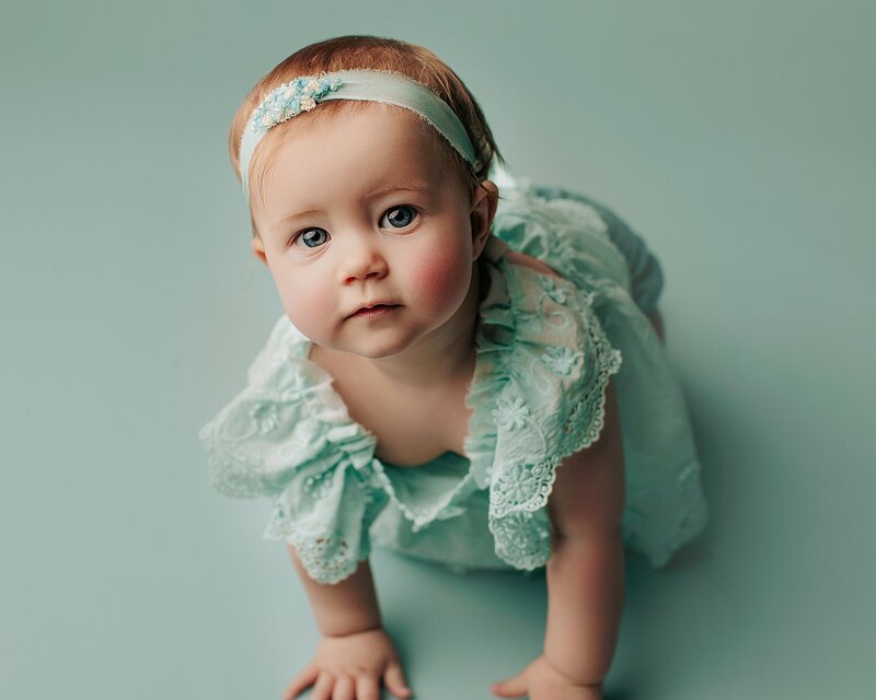 Baby reaching toward camera with happy expression during session