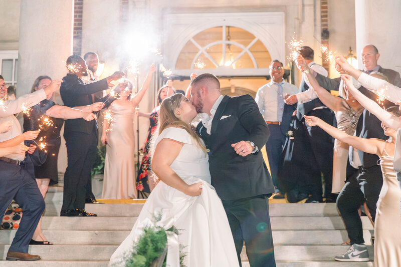 bride and groom kissing during their sparkler exit