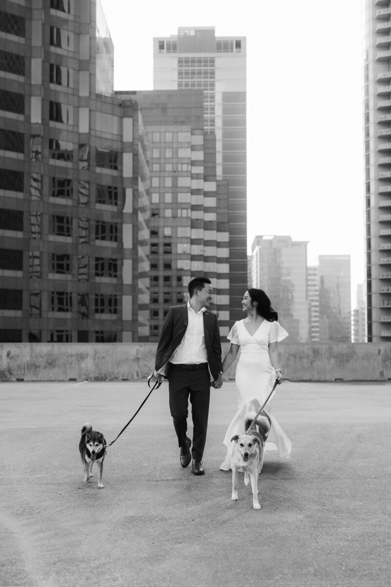 a black and white photo of an engaged couple walking their dogs on a rooftop in Austin, texas