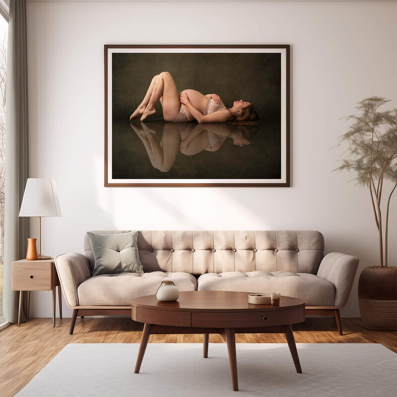 A large framed print of an expecting woman hangs in  a living room above a couch