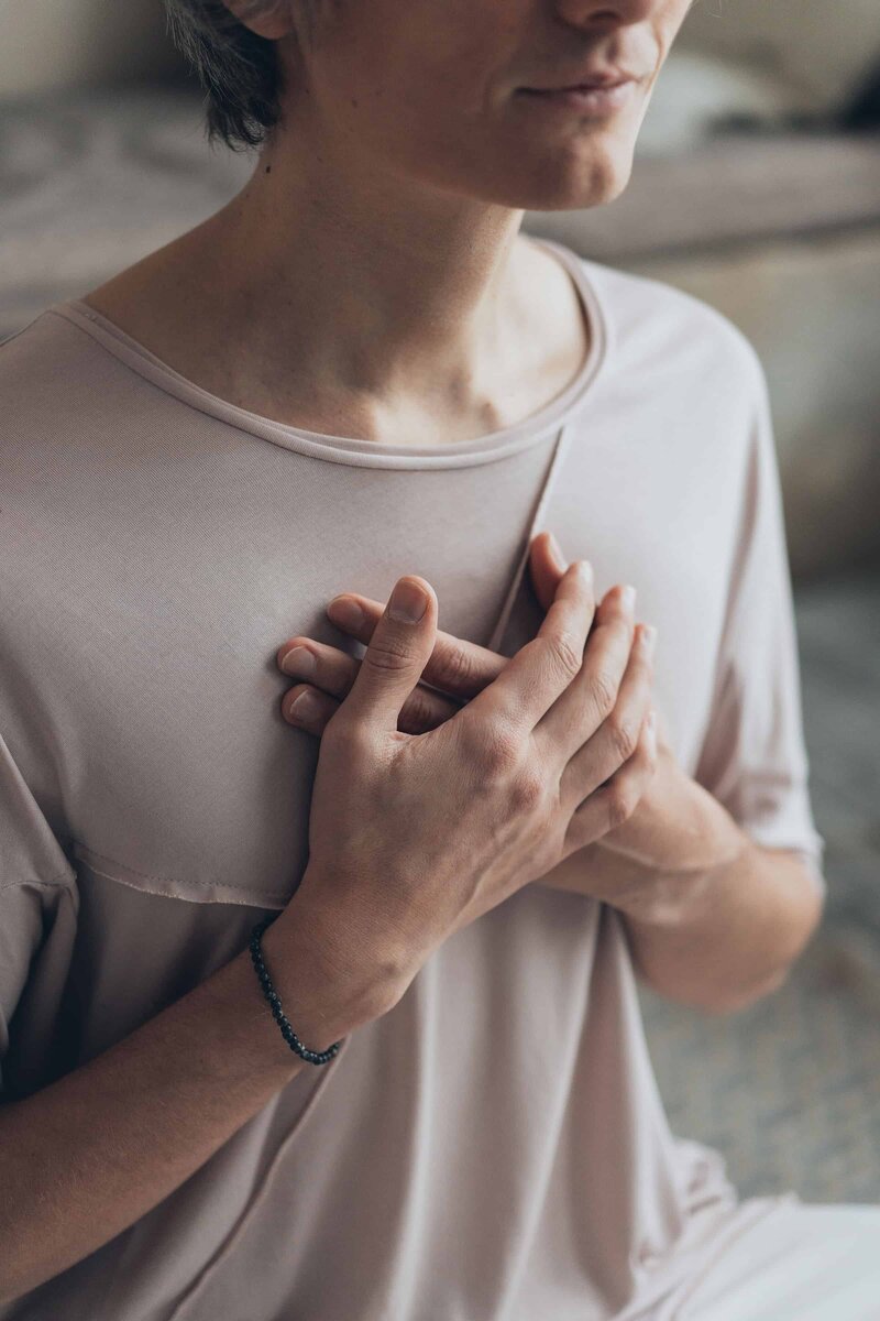 Person with both of their hands crossed on their heart, as if they're holding their heart in their hands.
