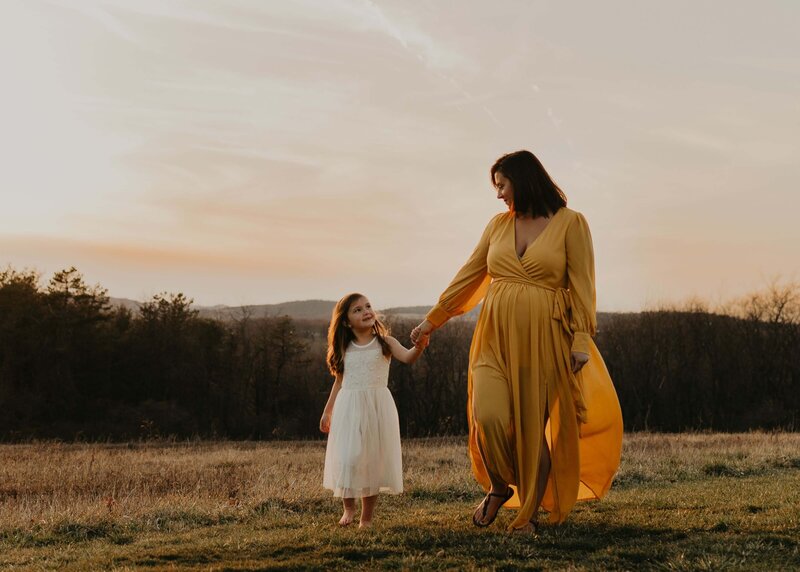 A prenant woman walking with her daughter during a maternity photo session near pittsburgh