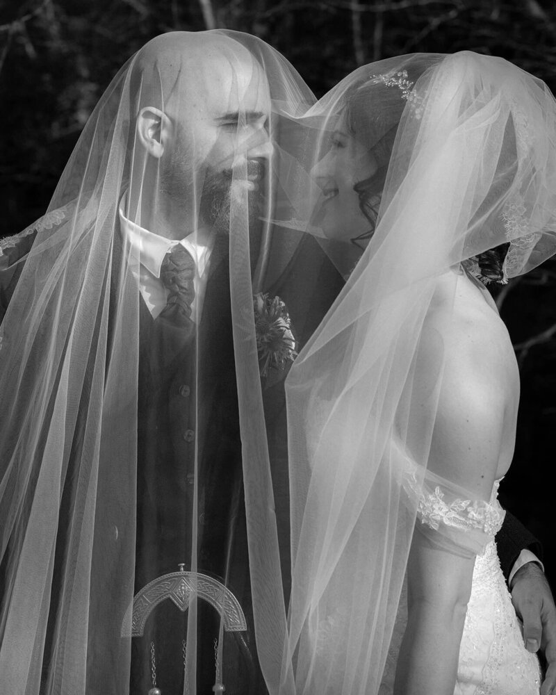 Americans getting married in a Scottish Castle. Bride and groom kissing under a veil 
