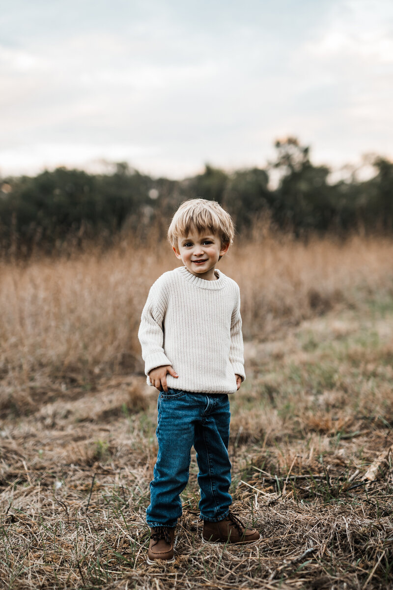 Two young brothers in teddy bear pajamas hugging outside.