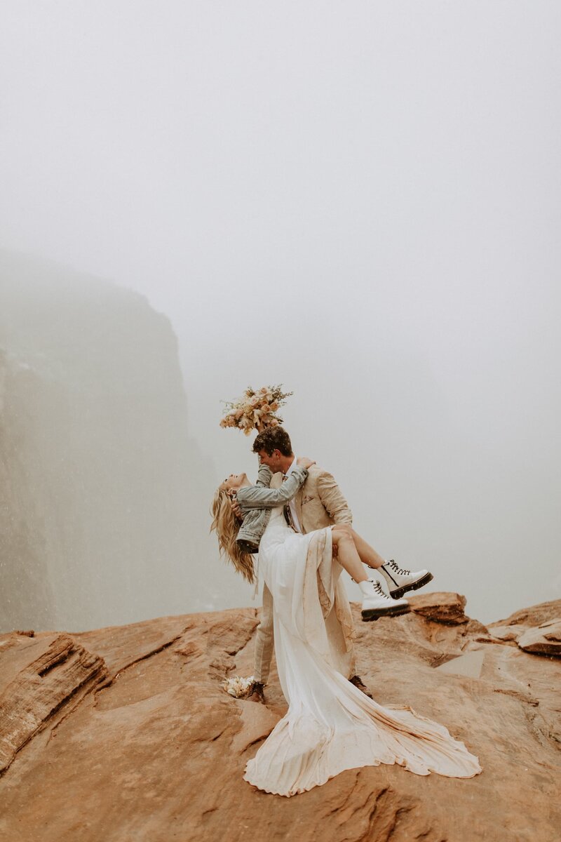 groom dipping bride on red rocks