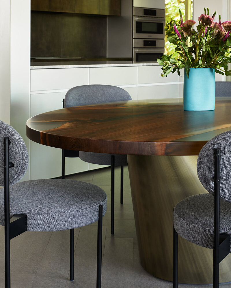 An elegant wood dining table surrounded by soft grey chairs