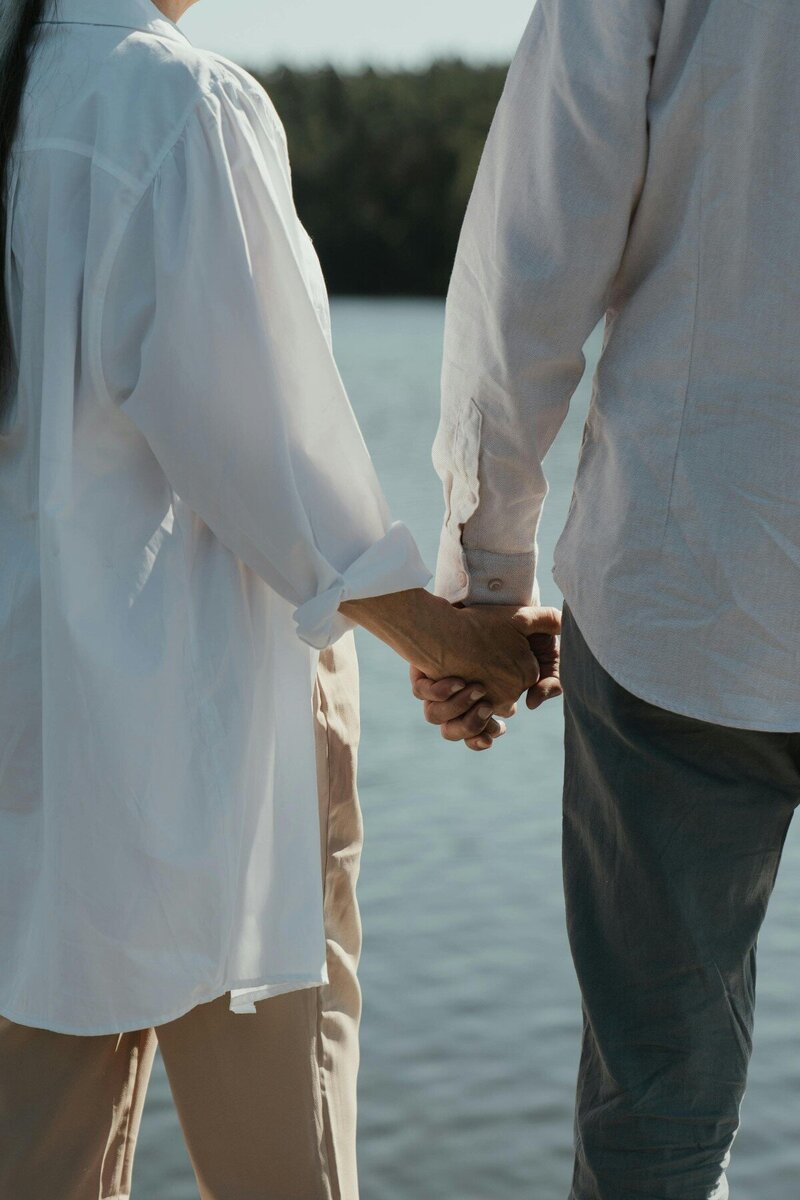 Married couple holding hands by water