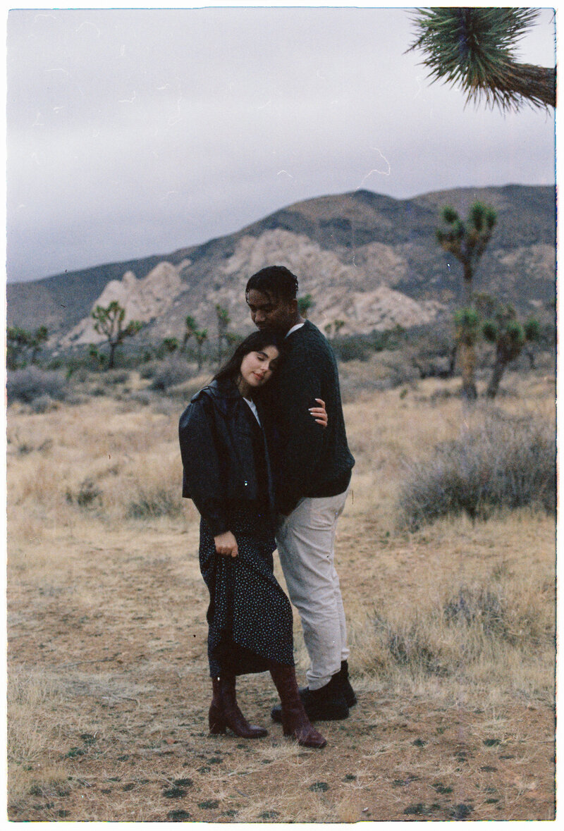Couple walking hand in hand sharing a kiss during their wedding day, captured in an artistic photojournalistic style with digital and film photography