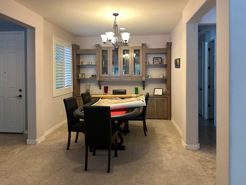 Dining room before interior design renovation in Peoria, AZ with neutral carpet and traditional cabinetry