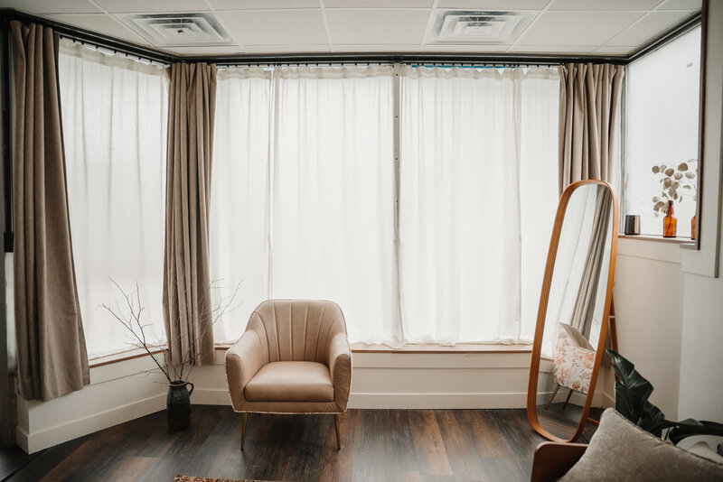 large natural light windows with simple tan lounge chair and tall mirror at a photography rental studio in bloomington illinois