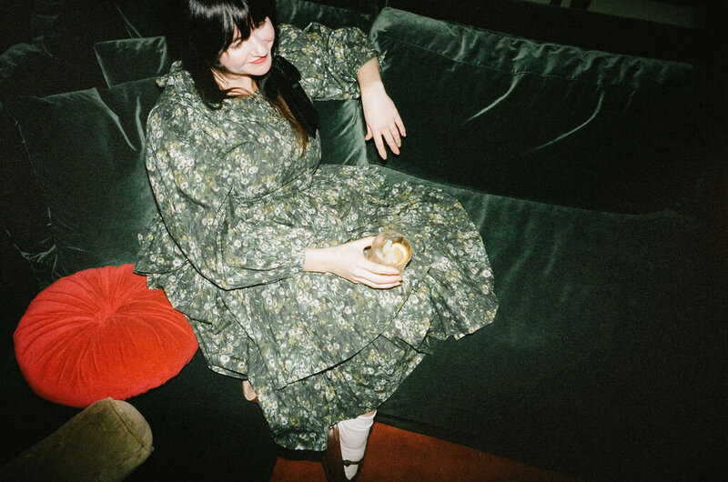 Woman sitting on a green couch with a cocktail
