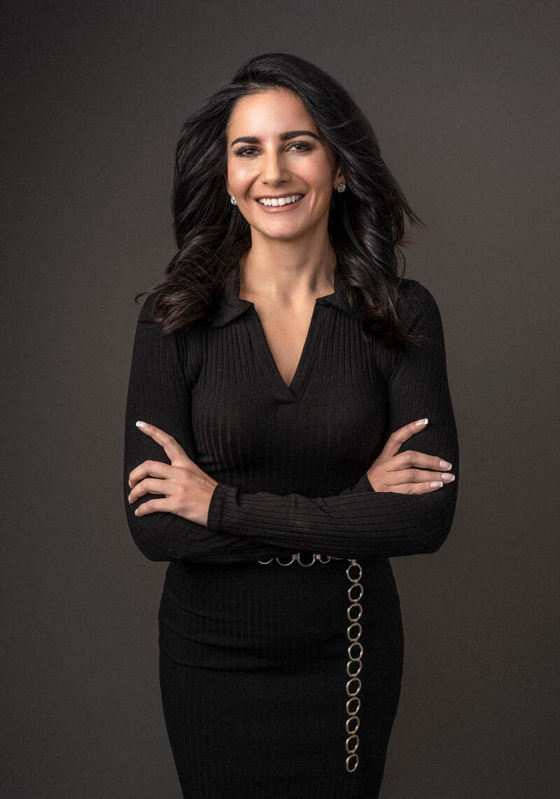 Confident woman in a black dress, professional studio portrait.