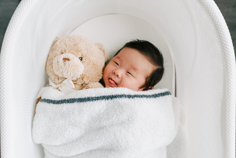 photo of a newborn asian boy tucked into snoo with teddy bear taken by a northern va photographer