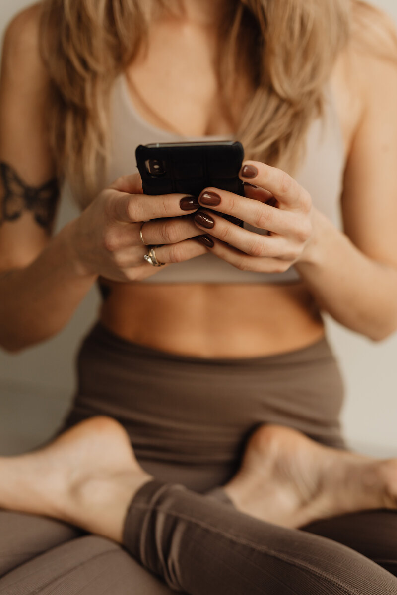 kaboompics_young-adult-woman-yoga-mat-brown-leggings-exercise-outfit-cell-phone-mobile-iphone-28709