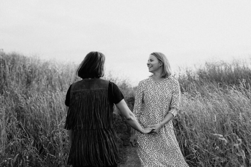 Adult sisters holding hands and dancing in the field of hay in Helsinki Finland.