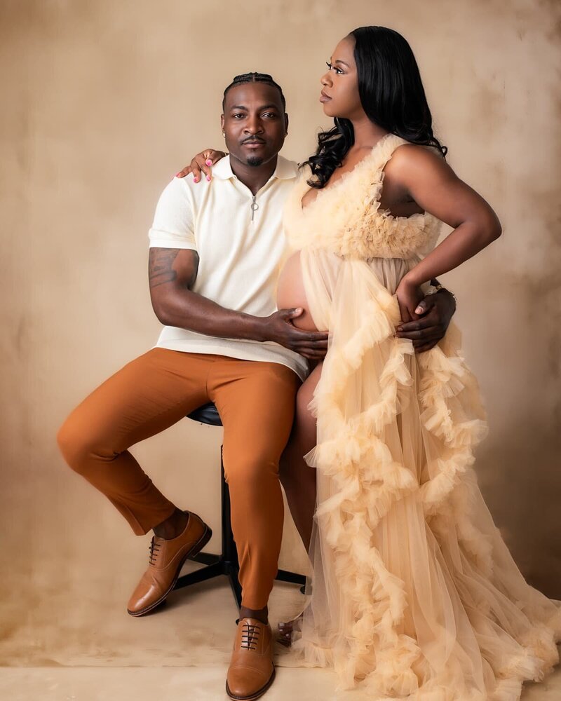 Expecting couple in a soft beige gown and warm-toned outfit during a Bump to Baby maternity photography session in Birmingham, Alabama