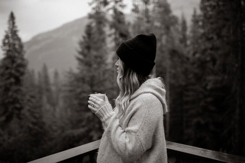 Woman holding coffee and looking out at the mountains